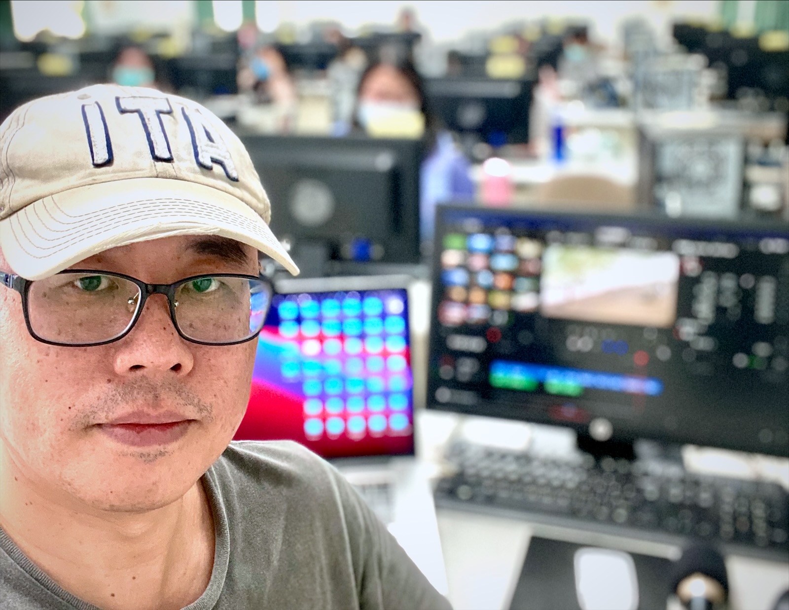 大蘇老師在電腦教室自拍，身後螢幕開著直播軟體，學員在後方上課